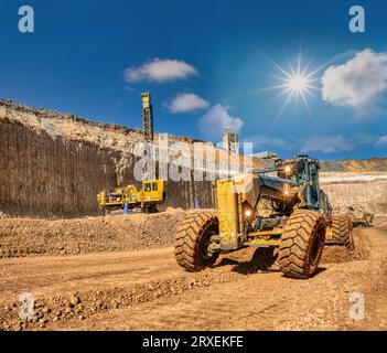 grader and drilling rig ,digging and loading kimberlite at the plant in the diamond mine ,daytime. Stock Photo