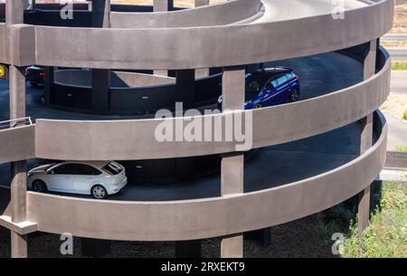 cars driving down on a mall multilevel parking lot , concrete structure parking built on pillars Stock Photo