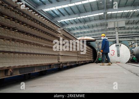 Luannan, China - February 13, 2023: Workers control traction equipment to transport new building materials - calcium silicate boards - from autoclaves Stock Photo