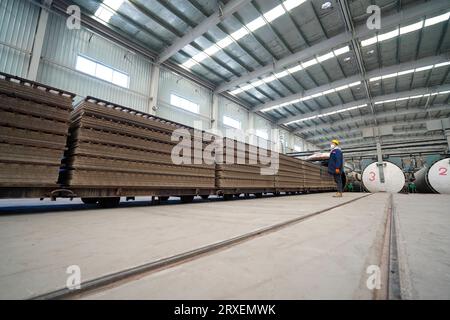 Luannan, China - February 13, 2023: Workers control traction equipment to transport new building materials - calcium silicate boards - from autoclaves Stock Photo