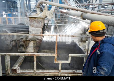 Luannan, China - February 13, 2023: Workers control traction equipment to transport new building materials - calcium silicate boards - from autoclaves Stock Photo