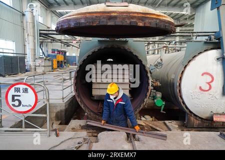 Luannan, China - February 13, 2023: Workers control traction equipment to transport new building materials - calcium silicate boards - from autoclaves Stock Photo