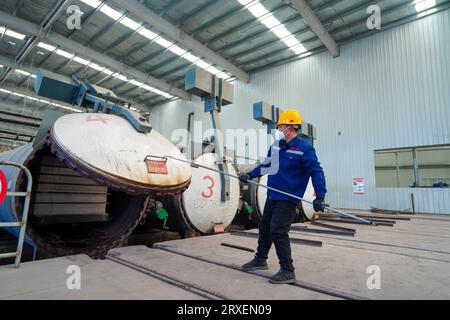 Luannan, China - February 13, 2023: Workers control traction equipment to transport new building materials - calcium silicate boards - from autoclaves Stock Photo