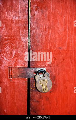 Old brass lock on a red wooden door. Stock Photo