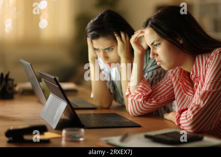 Worried tele workers checking bad news on tablet in the night at home Stock Photo