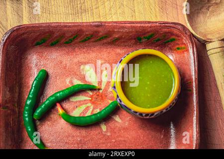 Green sauce on a clay plate decorated with jalapeno peppers. Stock Photo