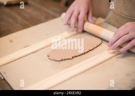Woman hands, pottery studio and painting cup in workshop for sculpture, creative manufacturing or design. Painter, ceramics product and brush process, Stock Photo