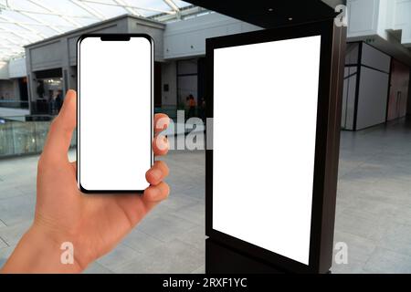Hand with phone on a background of self-service kiosk in the shopping mall. Stock Photo