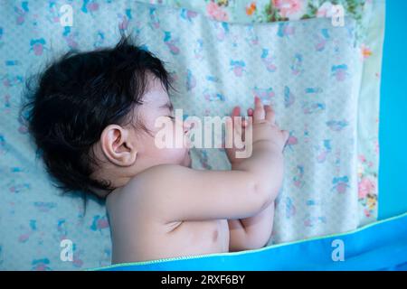 Small six months old cute indian baby boy with black hairs sleeping. Stock Photo