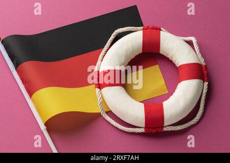 Piggy bank, lifebuoy and German flag on a colored background, concept on the theme of help from Germany Stock Photo