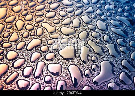 Abstract view of rain water drops on black metal surface, cross-processing effect applied Stock Photo