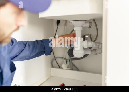 Close up of professional plumber installs a siphon pipe on the kitchen sink Stock Photo