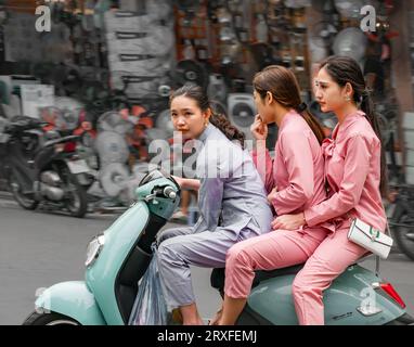 Three pretty young Vietnamese women riding on Vespa style moped, Hanoi, Vietnam, Asia Stock Photo