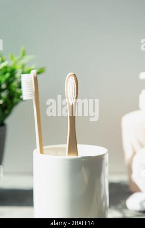 Natural bamboo toothbrushes, plant, towels on a light background. Wooden ecological toothbrushes. Stock Photo