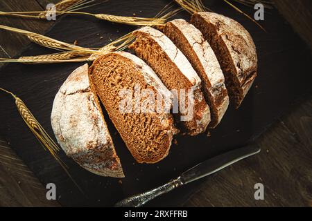 Freshly baked traditional bread on a wooden table. Sliced rye bread, close-up. Food background. Stock Photo