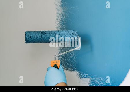 painting wall with blue paint roller. renovating home apartment Stock Photo