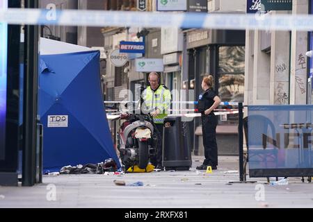 Police officers at the scene of a fatal collision on Tottenham Court Road, central London. A 18-year-old motorcyclist who was being followed by police has died after a crash with a taxi and street furniture at around 6.45am on Monday. The pillion passenger, who was found to have a machete, was taken to hospital for leg and arm injuries and arrested. Stock Photo