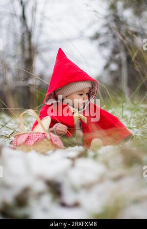 Baby in little red riding hood costume in snow Stock Photo