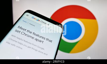 Mobile phone with website of web browser Google Chrome on screen in front of business logo. Focus on top-left of phone display. Stock Photo