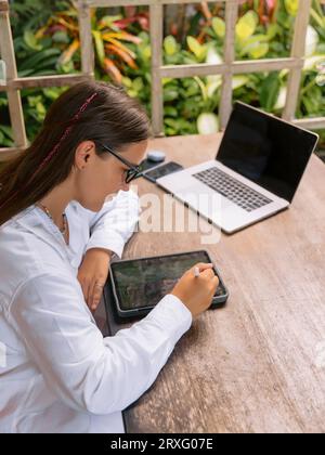 Young woman designer using digital tablet and laptop computer in outdoor office Stock Photo
