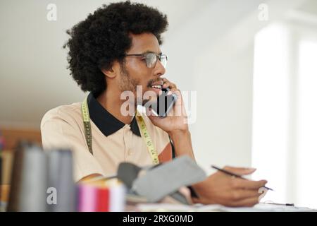 Portrait of fashion designer talking on phone with client Stock Photo