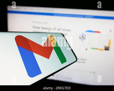 Smartphone with logo of email service Google Gmail on screen in front of business website. Focus on center-left of phone display. Stock Photo