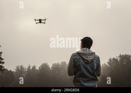 Professional photographer taking photos from drone. man taking aerial photos in forest. Man controlling his drone on background of mountain forest. Stock Photo