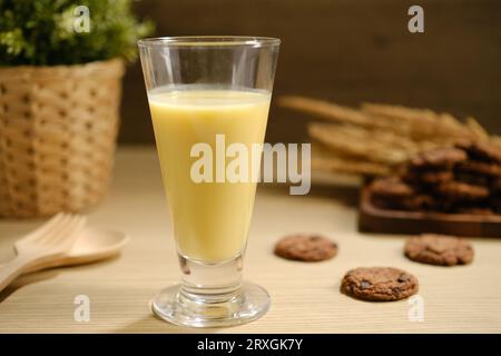 Tasty fresh corn milk in glass and cobs on white wooden table. Stock Photo