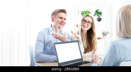 In the office, a seasoned female realtor offers guidance to a young couple on real estate purchase. Selective focus. Stock Photo
