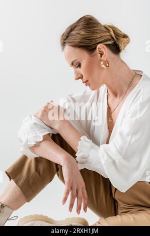 elegant pretty woman in formal pastel wear sitting on floor and looking down, style and fashion Stock Photo