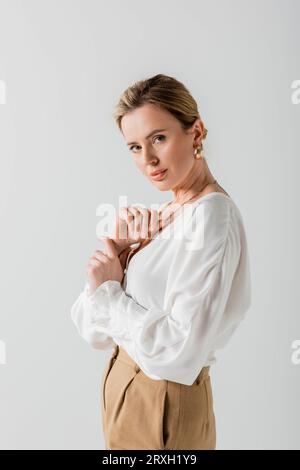 beautiful voguish blonde in pastel attire looking at camera with her arms close to chest, fashion Stock Photo