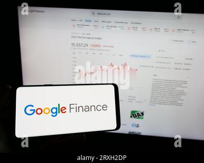 Person holding smartphone with logo of financial information platform Google Finance on screen in front of website. Focus on phone display. Stock Photo