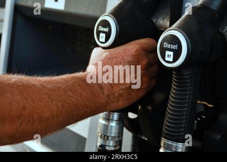 Refueling the car, a man's hand refills diesel fuel at the gas station and the gasoline pump fills the fuel nozzle in the car tank. Stock Photo