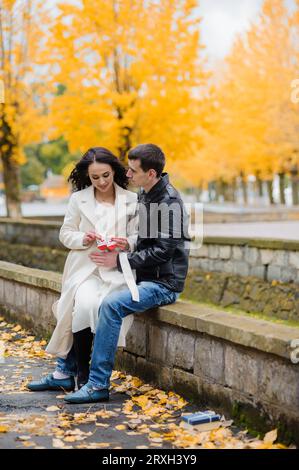 A pregnant woman sits on her husband's lap and holds small baby socks in her hands Stock Photo