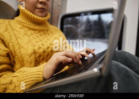 Close up of young woman using laptop in trailer van with focus on female hands typing, copy space Stock Photo
