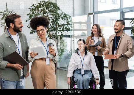 diversity and inclusion, disabled woman in wheelchair near interracial coworkers with name tags Stock Photo