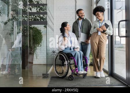 group shot of diverse business people, disabled woman on wheelchair chatting with colleagues Stock Photo