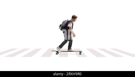 Full length profile shot of a schoolboy in a uniform riding a skateboard at a pedestrian crossing isolated on white background Stock Photo