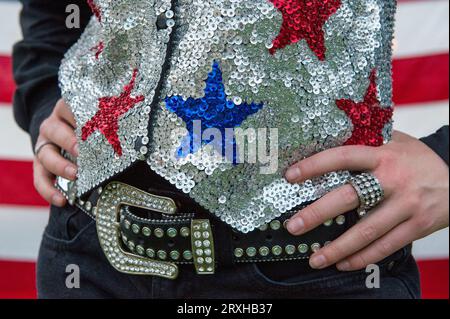 Close up of a rodeo queen's belt and sequined vest in front of an American flag; Burwell, Nebraska, United States of America Stock Photo