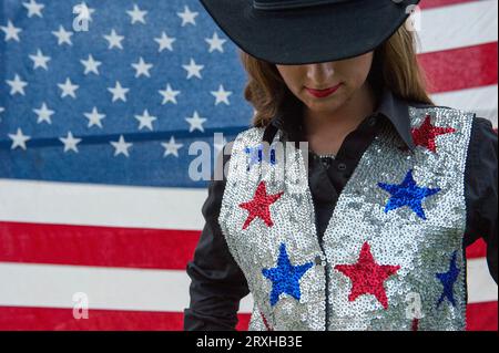 Rodeo queen poses for a portrait in front of an American flag; Burwell, Nebraska, United States of America Stock Photo
