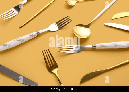 Golden and silver cutlery on orange background Stock Photo