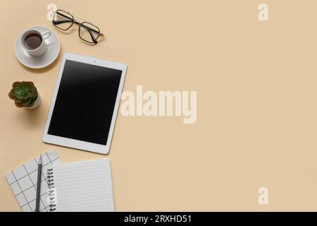 Tablet, cup of coffee and stationery on beige background Stock Photo