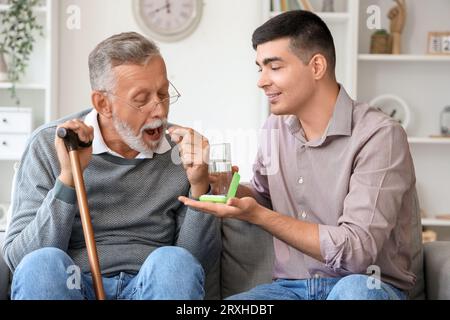 Senior man with his son taking pills at home Stock Photo