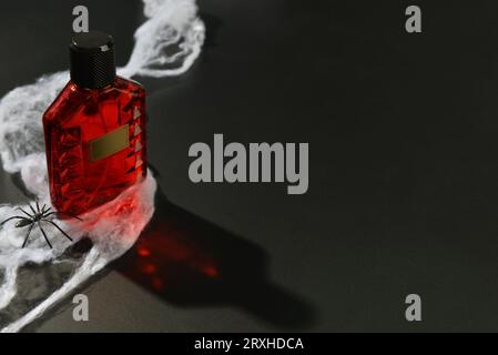 Bottle of elegant perfume with spiderweb for Halloween celebration on black background Stock Photo