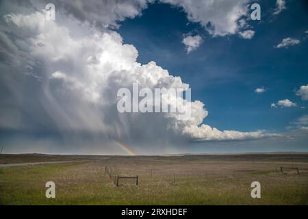 Huge thunderhead dumping rain and hail on the prairie of Southeast Wyoming providing a wonderful rainbow for those on this side of the storm Stock Photo