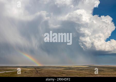 Huge thunderhead dumping rain and hail on the prairie of Southeast Wyoming providing a wonderful rainbow for those on this side of the storm Stock Photo