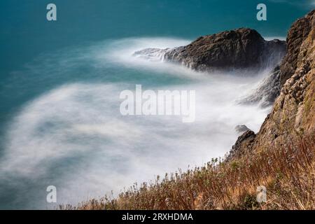 Long exposure of frothy waves crashing into the cliffs at Cape Disappointment, at the mouth of the Columbia River in Southwest Washington Stock Photo