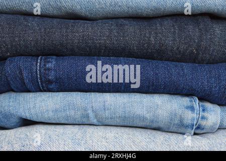 Neatly folded stack of clothes - jeans in different shades of blue Stock Photo