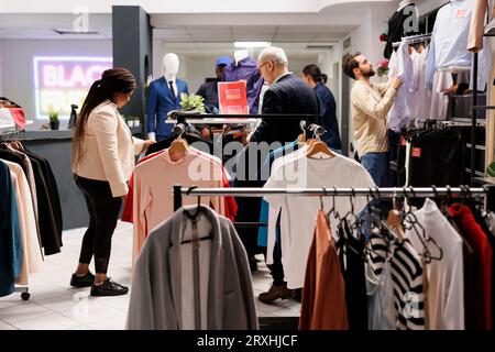 Shopaholism and Black Friday. Shopaholic diverse people consumers looking for new fashionable trendy clothes in clothing store, customers visiting fashion outlet, shopping during sale season Stock Photo