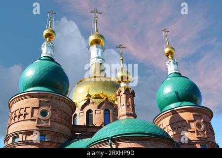 Three domes with crosses (one golden and two green) of the Orthodox Church, blue sky. Stock Photo